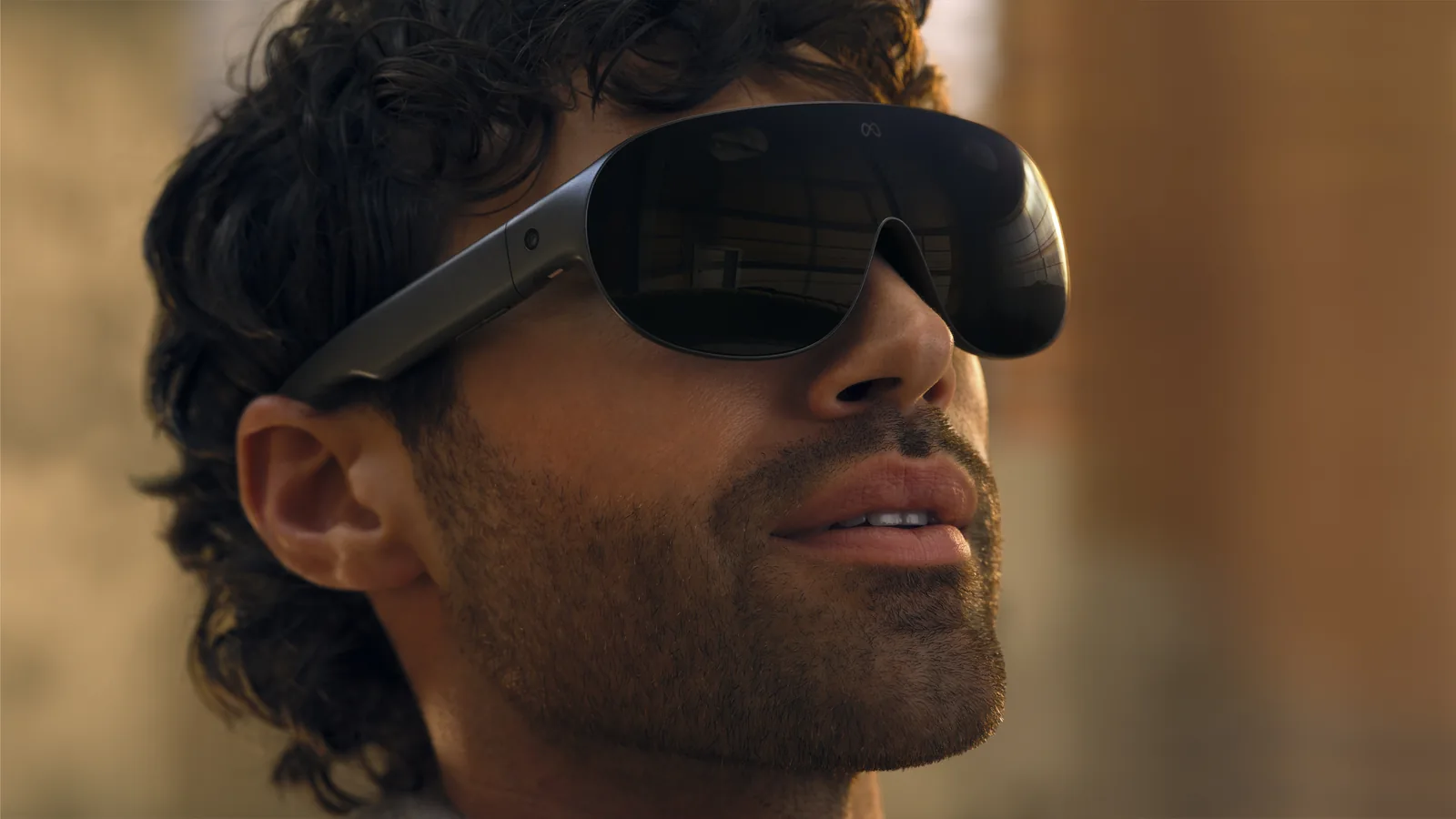 Meta VR Glassesを装着した男性の横顔。サングラスに近い薄型のフレームで、つるの部分からケーブルが伸びている
